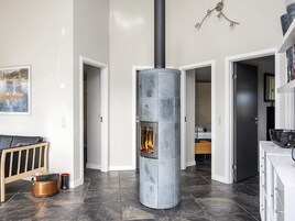 Um interior moderno com uma lareira de pedra central, um banco de madeira e uma lixeira preta.