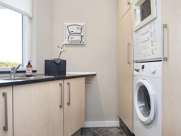 A modern kitchen with a built-in washing machine, a sink with a faucet, and a vase with flowers on the countertop.