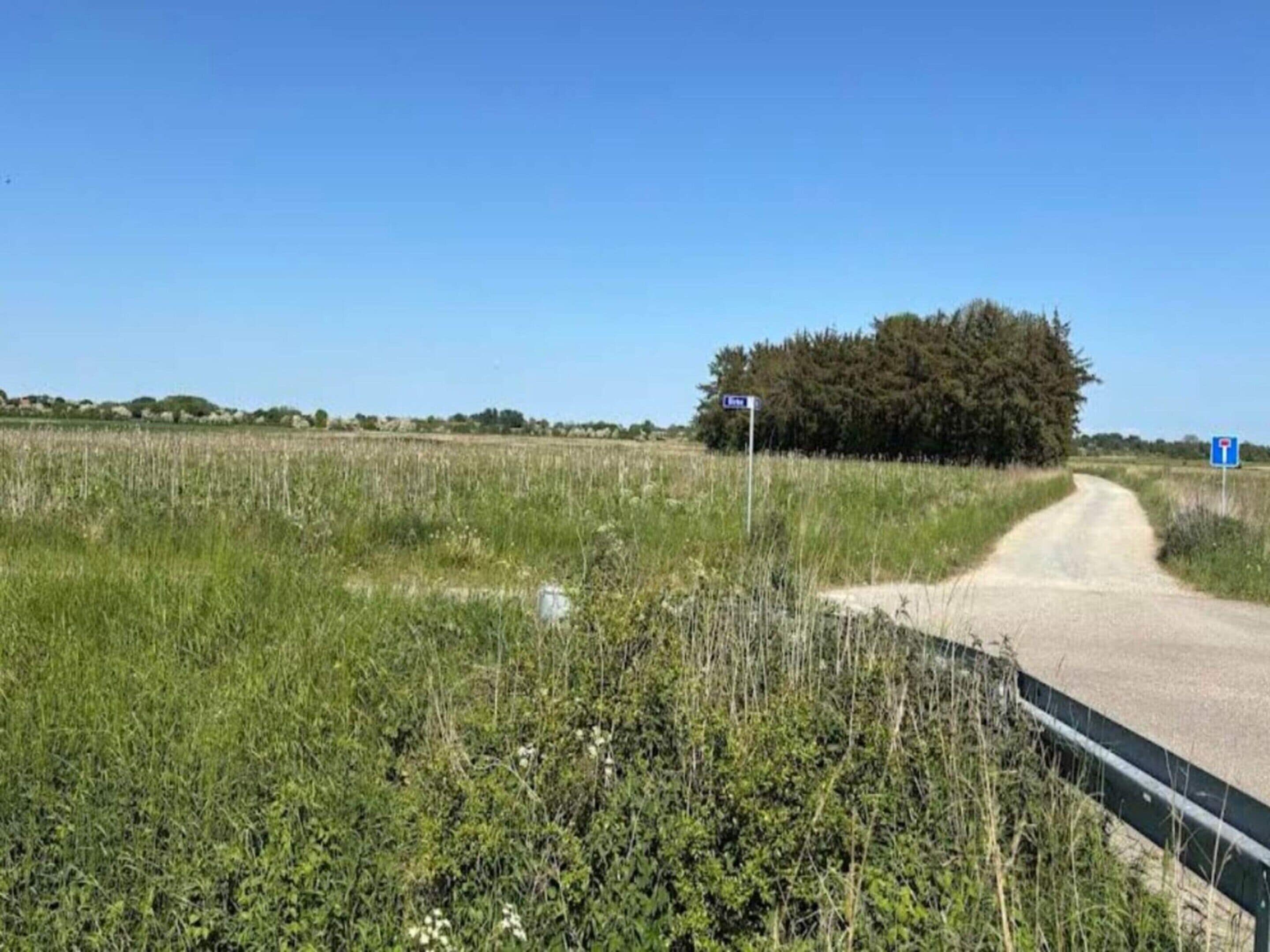 Een landelijke weg met een blauw bord dat een parkeerplaats aangeeft.