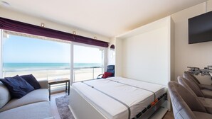 Una habitació d'hotel amb un llit, un sofà, una cadira, una taula petita i una televisió.