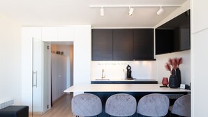 Una cuina moderna amb una illa central, tamboretes i forn integrat.