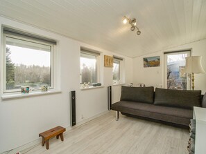 Una habitación con sofá, banco y ventana con vistas a árboles.