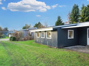 A single-story mobile home with a dark exterior, a small porch, and a clear sky. - 4 Person Holiday Home in Grevinge (Grevinge)