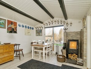 A cozy room with a fireplace, wooden furniture, and wall-mounted deer antlers. - 4 Person Holiday Home in Grevinge (Grevinge)