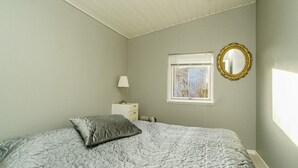 A bedroom with a bed, a nightstand, a lamp, a window, and a mirror. - 4 Person Holiday Home in Grevinge (Grevinge)