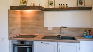A kitchen with wooden cabinets, a double sink, and a built-in oven. - Lovely Apartment in Straelen (Straelen)