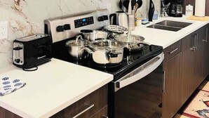 Une cuisine moderne avec des meubles de couleur bois foncé, un plan de travail blanc, un four encastré et une hotte aspirante.