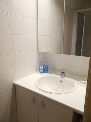 A bathroom with a white sink, a mirror, and a toothbrush holder with a toothbrush. - Apartment in Nieuwpoort Near the Beach (Nieuwpoort)