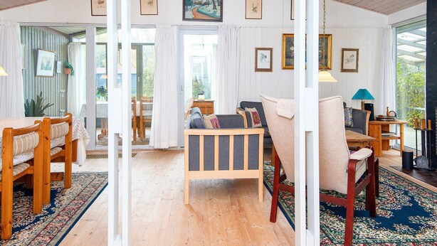 A spacious room with a high ceiling, wooden floors, a sofa, a dining table with chairs, and a view through an open door. - 8 Person Holiday Home in Farvang (Farvang)