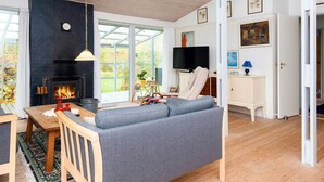 A cozy living room with a fireplace, a sofa, a TV, and a dining area. - 8 Person Holiday Home in Farvang (Farvang)