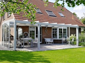 A house with a covered patio, a brick exterior, and a tiled roof.