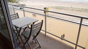 A balcony with a table and chairs overlooking a beach. - Apartment in Nieuwpoort With Coastal Views (Nieuwpoort)