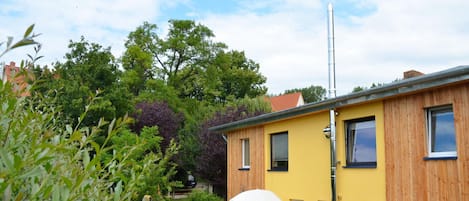 A yellow building with a wooden facade, a chimney, and a satellite dish.
