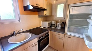 A compact kitchen with a sink, stove, microwave, and a refrigerator. - Gemutliche Ferienwohnung auf der Insel Poel (Insel Poel)