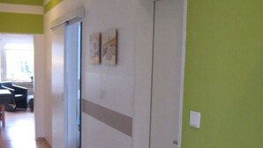 A hallway with a wooden floor, a green wall, and a white door. There are two framed pictures on the wall. - - 2 min zum Strand (Borkum)