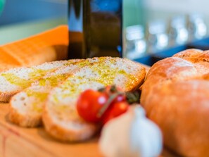 A wooden cutting board with sliced bread, a whole loaf of bread, and a small bunch of cherry tomatoes.
