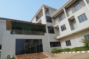 A multi-story building with a modern design, featuring balconies, large windows, and a covered entrance area.