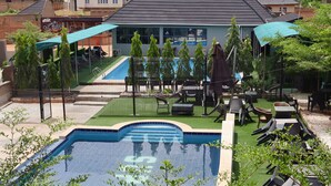 Una piscina con borde de azulejos, rodeada de césped artificial y mobiliario de exterior.