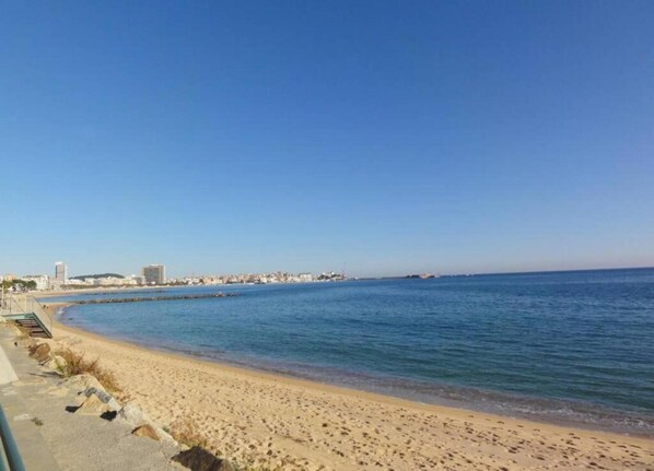 Una playa con una vista despejada del mar y un paisaje urbano al fondo.