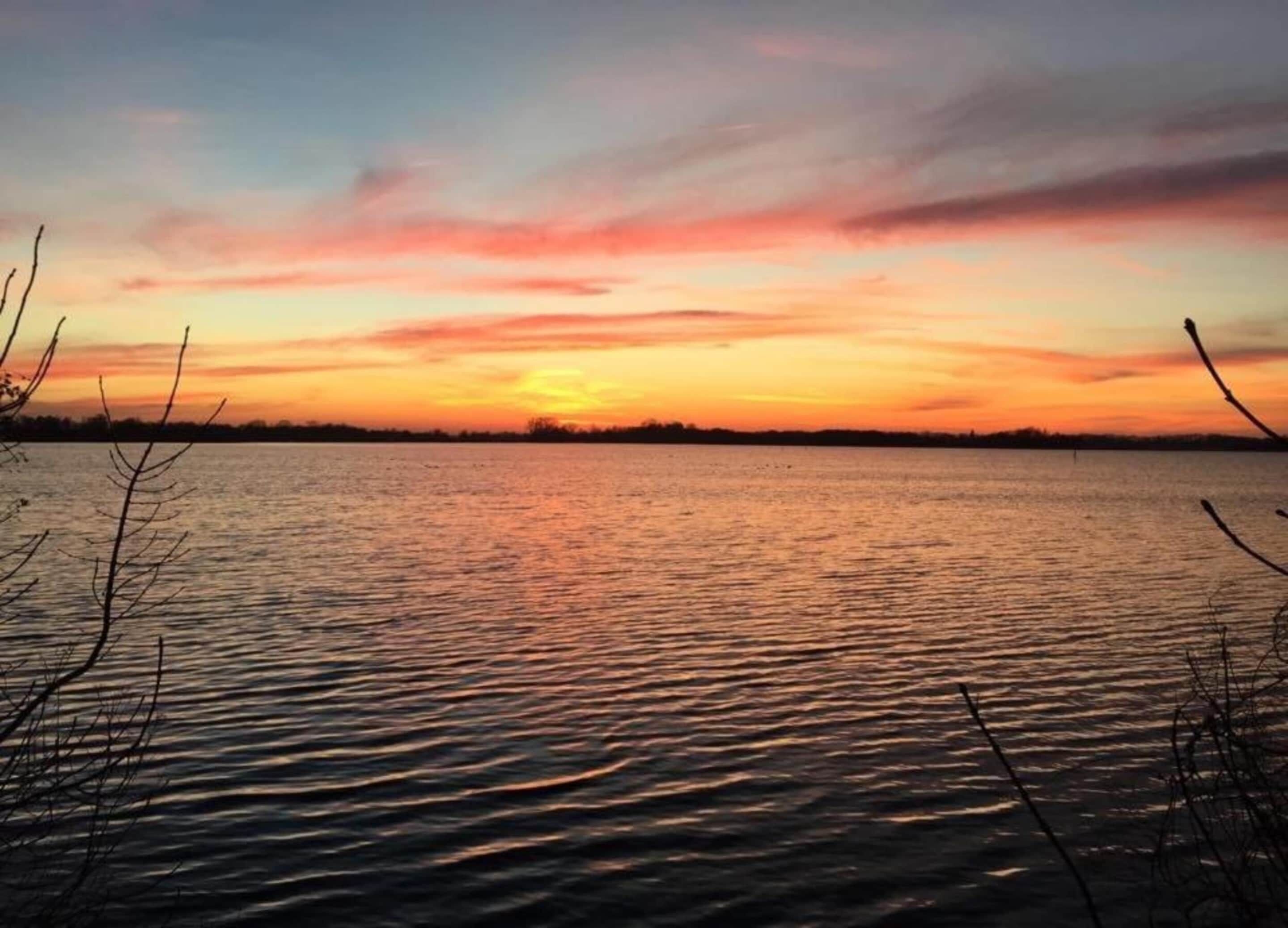 Un lago tranquilo al atardecer con cielo despejado.