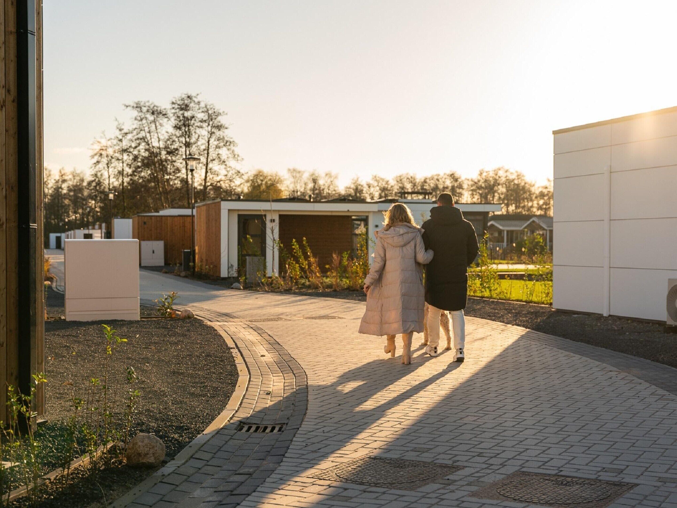 A pathway leading to a modern building with a garage and a small garden area.