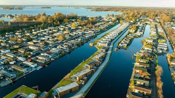 Een woonwijk met huizen langs een gracht, bestaande uit een mix van gelijkvloerse en meer verdiepingen tellende gebouwen, met zichtbare groenvoorzieningen en bomen.