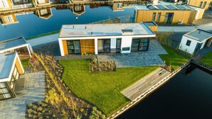 A modern house with a flat roof, large windows, and a well-maintained lawn. - Loosdrecht Water Villa (Loosdrecht)