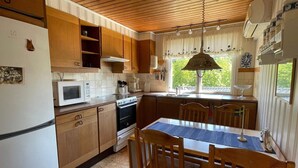A kitchen with wooden cabinets, a microwave, an oven, and a dining table with chairs. - 5 Person Holiday Home in Nosund-by Traum (Nosund)