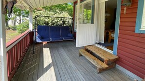 A wooden porch with a swing seat, a bench, and a door leading inside. - 5 Person Holiday Home in Nosund-by Traum (Nosund)