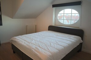 A bedroom with a bed, a window with a view, and a radiator.