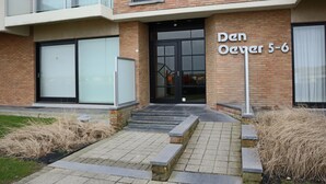 Un bâtiment moderne avec une façade en briques, de grandes fenêtres en verre et une enseigne indiquant « Den Oever 5-6 ».