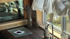 Een landelijke keuken met een houten aanrecht, een roestvrijstalen spoelbak en een raam met witte gordijnen.