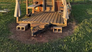 Een houten chalet met een veranda, een welkomstbord en een bank.