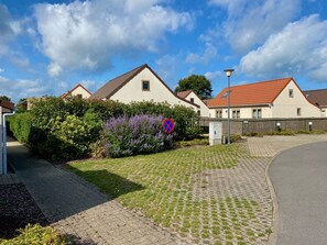 Un quartier résidentiel avec des maisons, une allée pavée et un panneau indiquant qu’il est interdit de se garer.