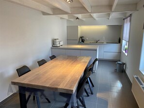 Une cuisine moderne avec un îlot central, une table à manger avec des chaises et une fenêtre agrémentée d’une plante.