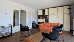 Uma sala de estar moderna com sofá, cadeiras, mesa de madeira e armários embutidos.