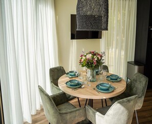 A round dining table with blue plates, a vase of flowers, and a hanging light fixture.
