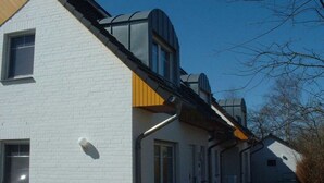A white building with a sloped roof and a small attached structure with a dark roof. - Bernsteinfinder 4.17 Comfortable Holiday Residence (Zingst)