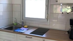 Eine Küche mit Fenster, weißen Schränken, einer Spüle und einer Kaffeemaschine.