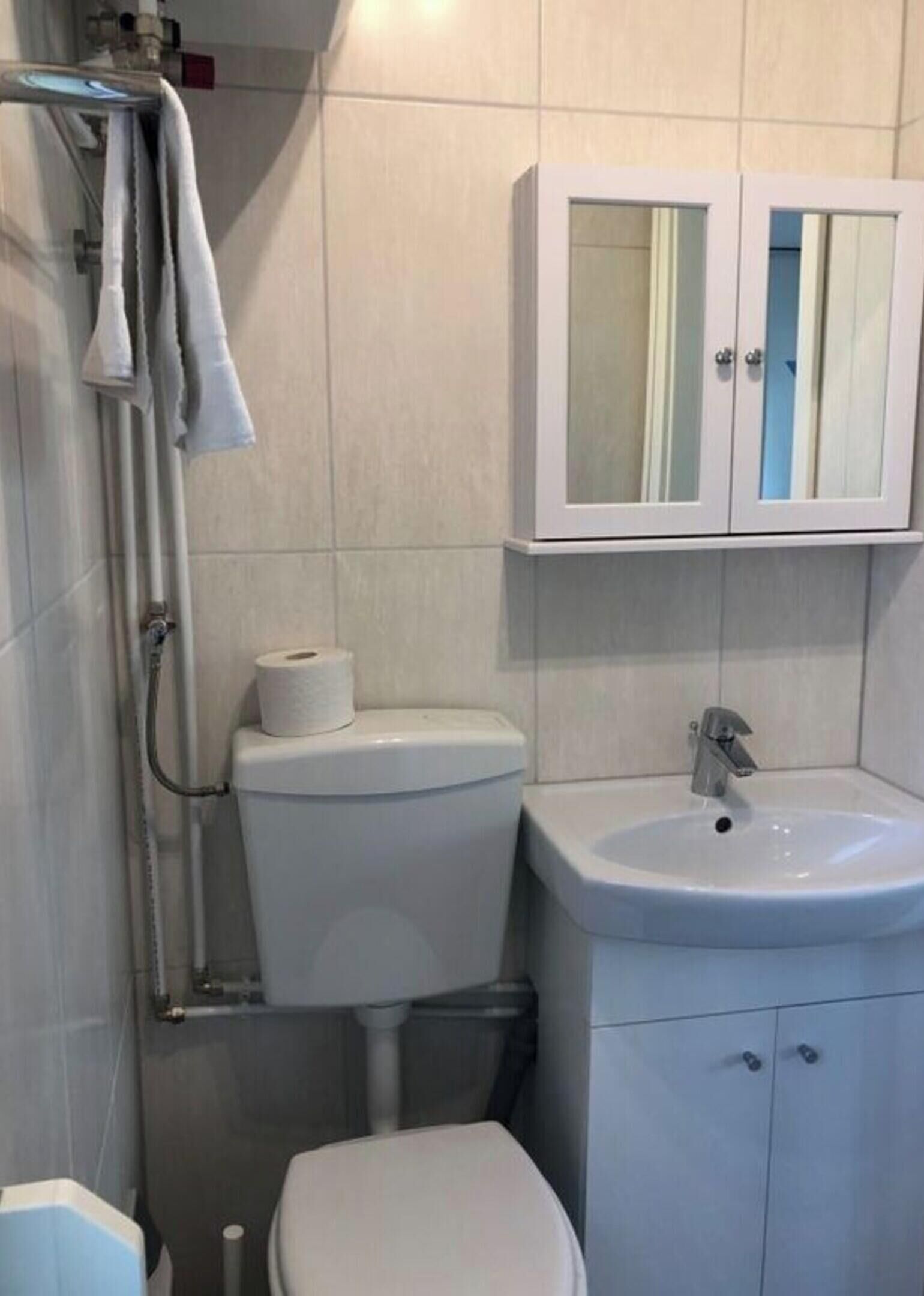 A bathroom with a toilet, sink, and cabinet.
