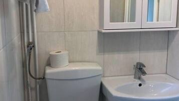 A bathroom with a toilet, sink, and cabinet.