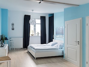 A bedroom with a bed, a desk, a chair, and a window with curtains. - Our-island-scharbeutz (Scharbeutz)