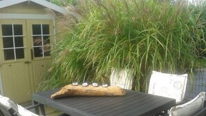 A patio table with a log centerpiece, surrounded by chairs with newspaper seat covers. - Our-island-scharbeutz (Scharbeutz)