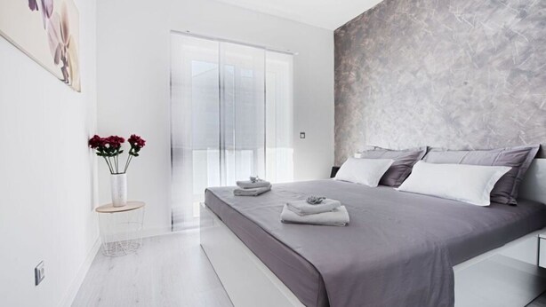 A modern bedroom with a large bed, a view of the outdoors, and a minimalist design. - Cosy Apartment in Pag (Pag)
