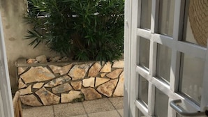 A stone wall with a tiled floor leading to a door with a metal handle. - Apartment Oleander (Novalja)
