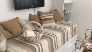 A neatly arranged bedroom with a bed, pillows, a basket, a lamp, and a magazine on a table. - Apartment Oleander (Novalja)