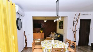 Ein Essbereich mit einem runden Tisch, der mit einer blumigen Tischdecke bedeckt ist, umgeben von Holzstühlen.