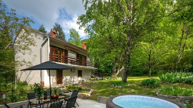 Ein Haus mit Terrasse, Sitzgelegenheit im Freien und einem Whirlpool.