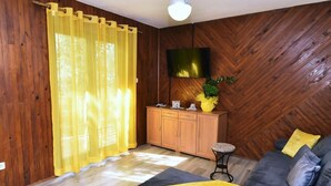 Ein Zimmer mit Holzwänden, einer Couch, einem Fernseher und einem Schrank.