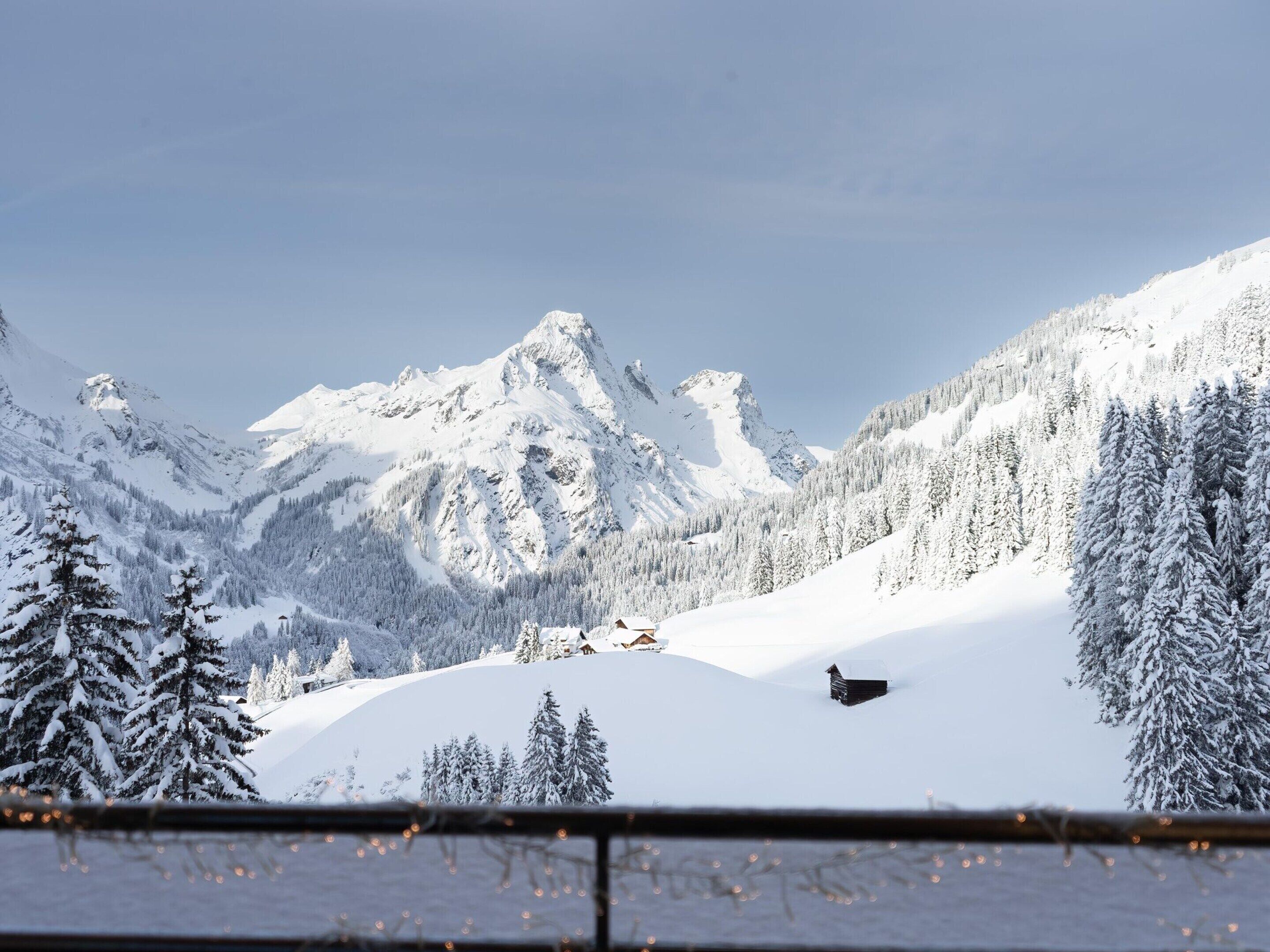 A snow-covered mountain landscape with a cabin and a small building in the foreground.